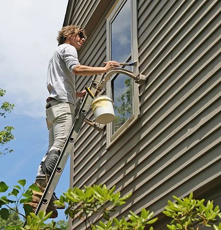 Exterior painting of the house at a height on the ladder