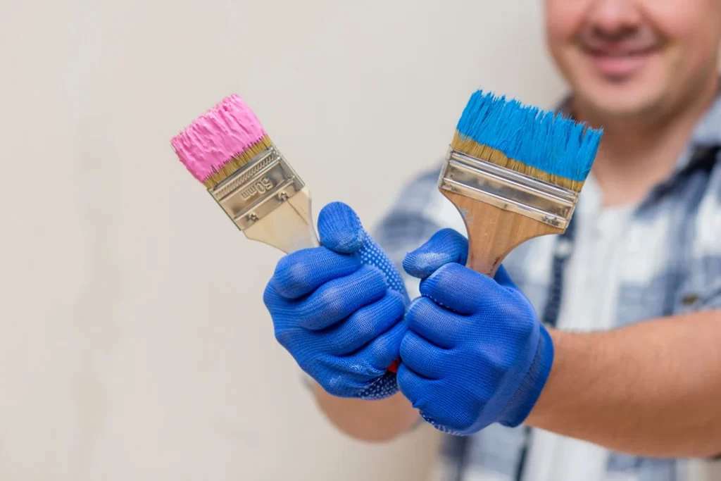 smiling man holding pink blue paint brush